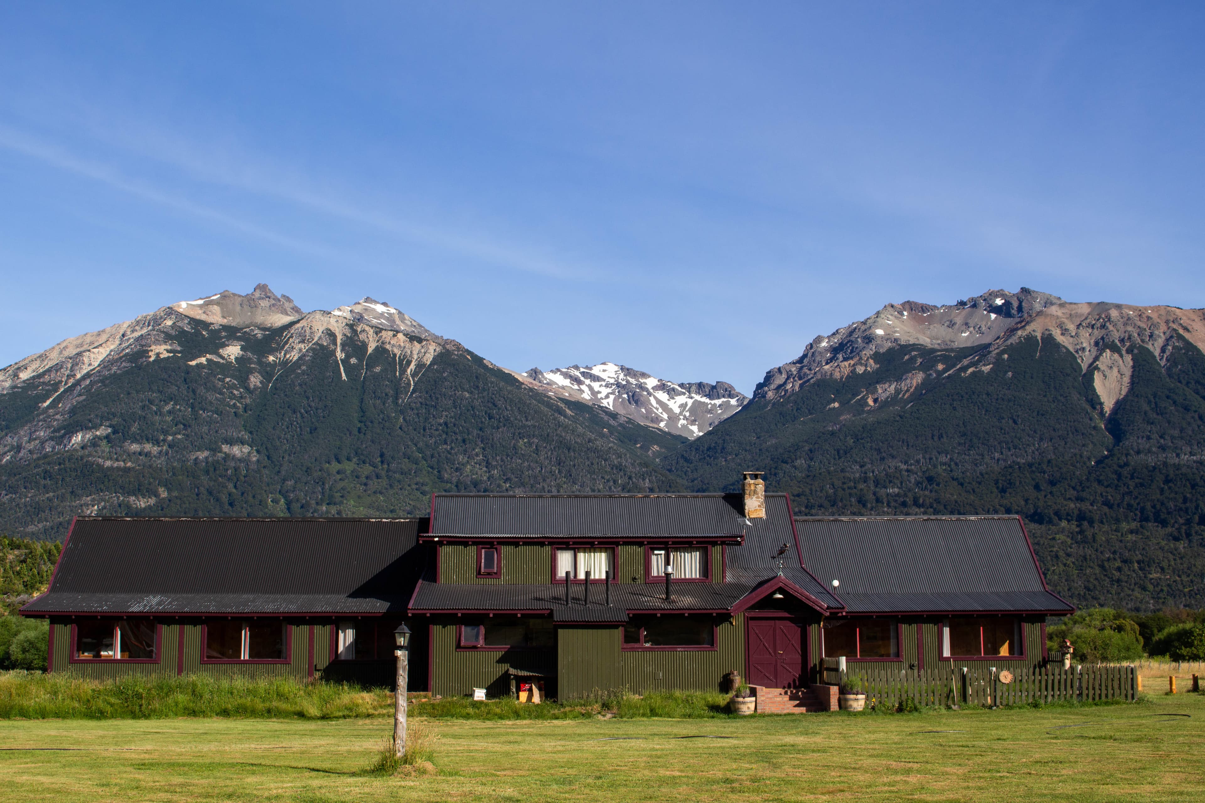 Instalaciones de La Pilarica Lodge junto a dos caballos, con montañas de fondo