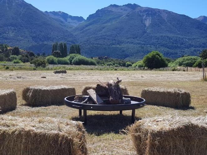 Instalaciones de La Pilarica Lodge junto a tres autos y montañas nevadas de fondo