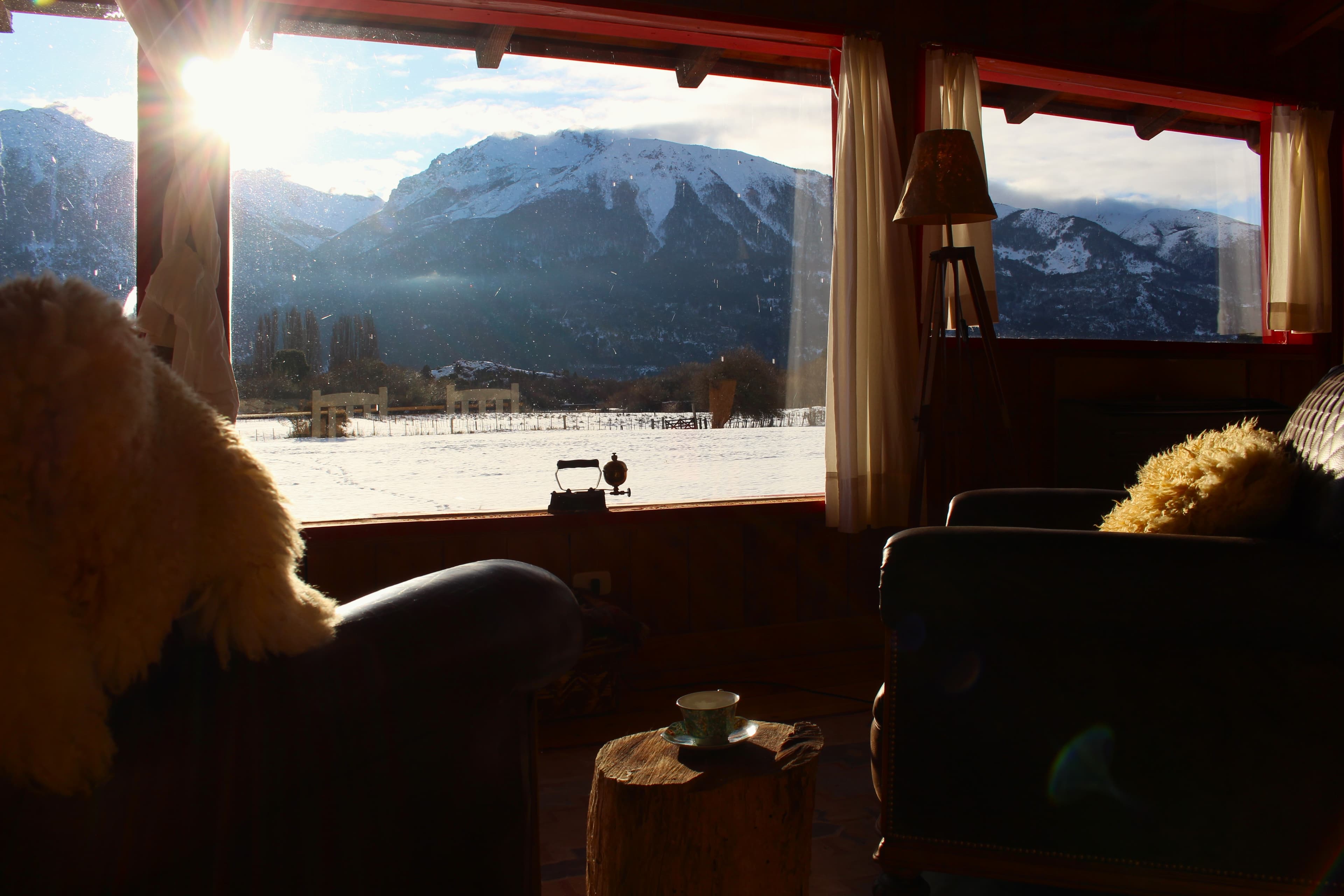 Instalaciones de La Pilarica Lodge junto a tres autos y montañas nevadas de fondo