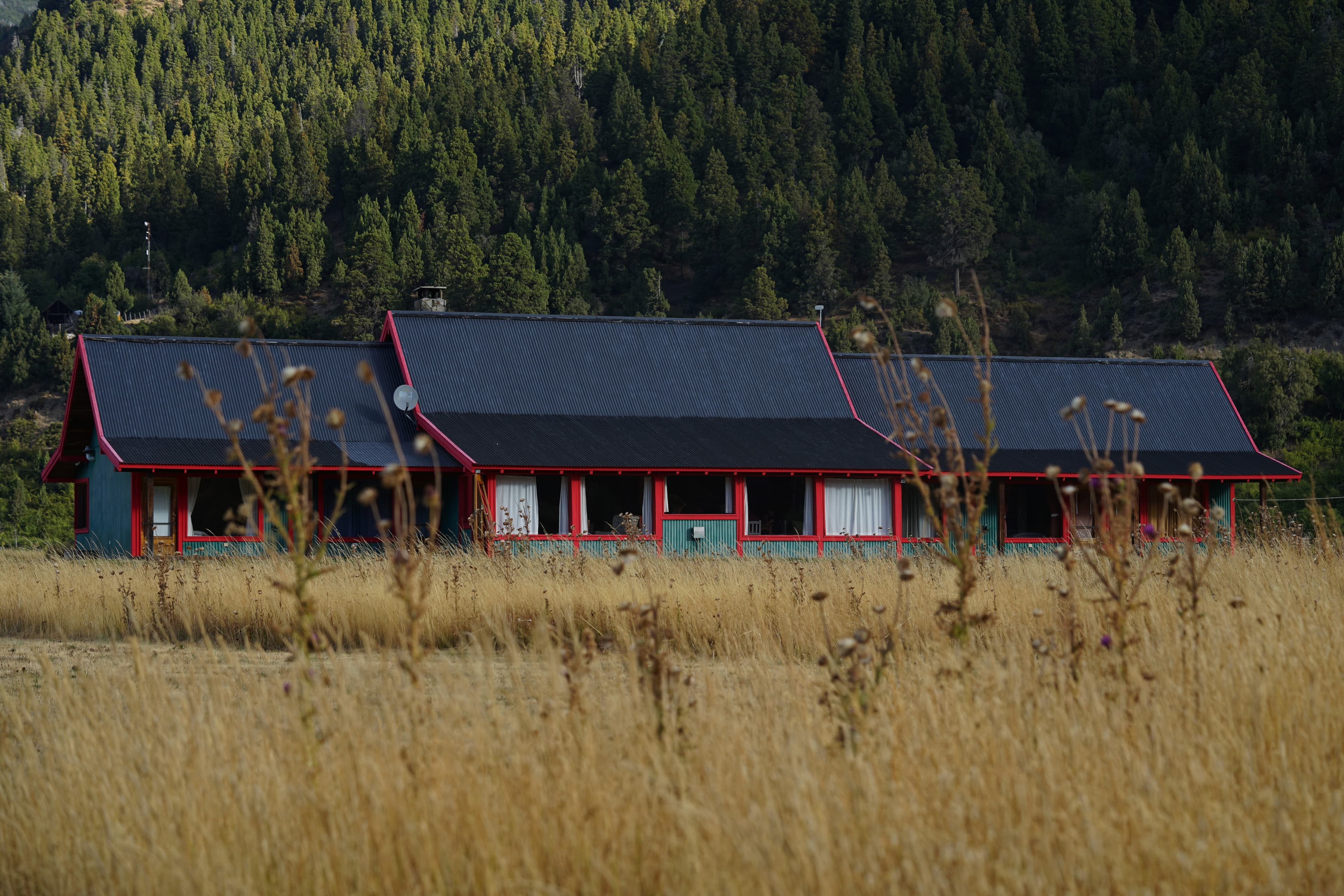 Facilities of La Pilarica Lodge with three cars and snowy mountains in the background