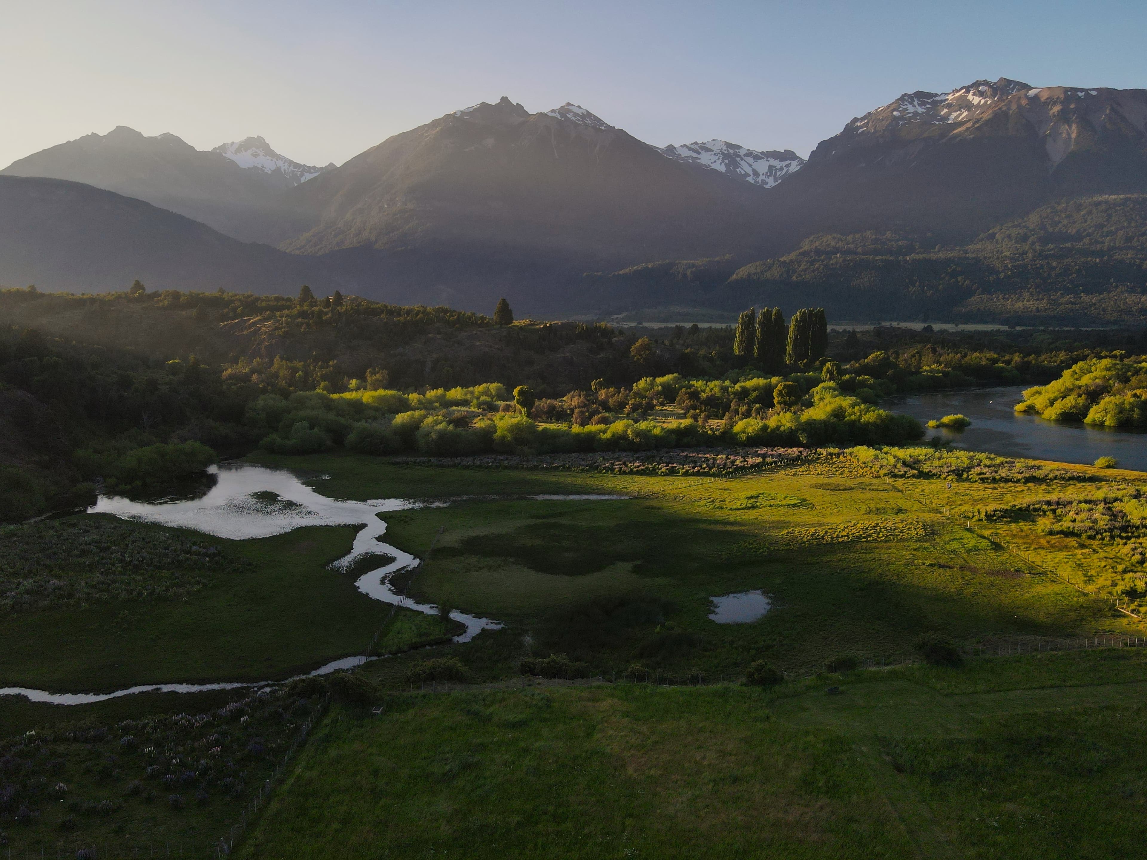 Instalaciones de La Pilarica Lodge junto a tres autos y montañas nevadas de fondo